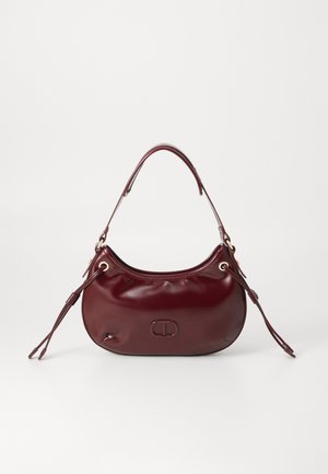 Burgundia värvi nahast käekott, millel on ümar kuju, üks pealmine käepide ja külgedel nööriga kaunistused. Ees on logo detail.