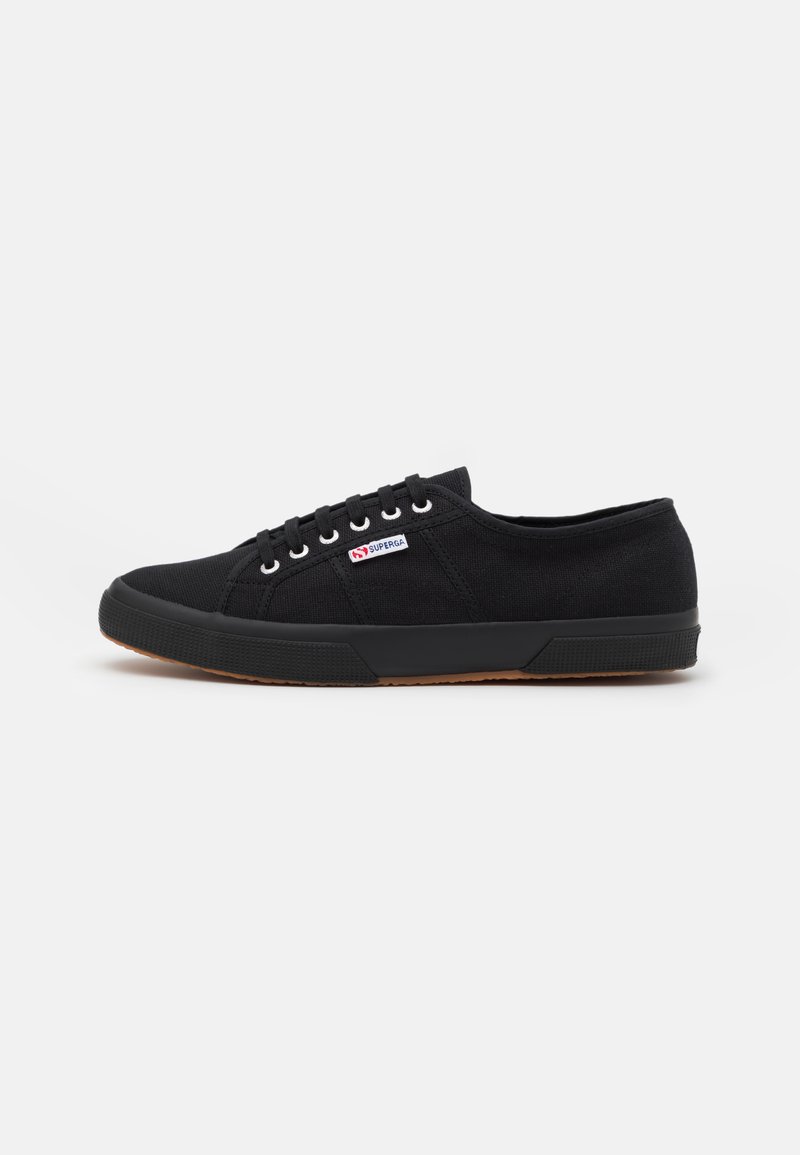 Sneakers neri in tela con punta tonda, occhielli bianchi, lacci neri e suola in gomma. Presentano un piccolo logo rosso e blu sul lato.