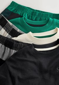 Trois T-shirts empilés : noir avec une finition texturée, vert et crème avec des encolures côtelées, plus un short à motifs avec une taille élastique.