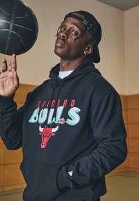 Felpa nera con grafica "Chicago Bulls" in rosso e turchese, con logo di un toro rosso. Tessuto di cotone liscio e tasca a marsupio.