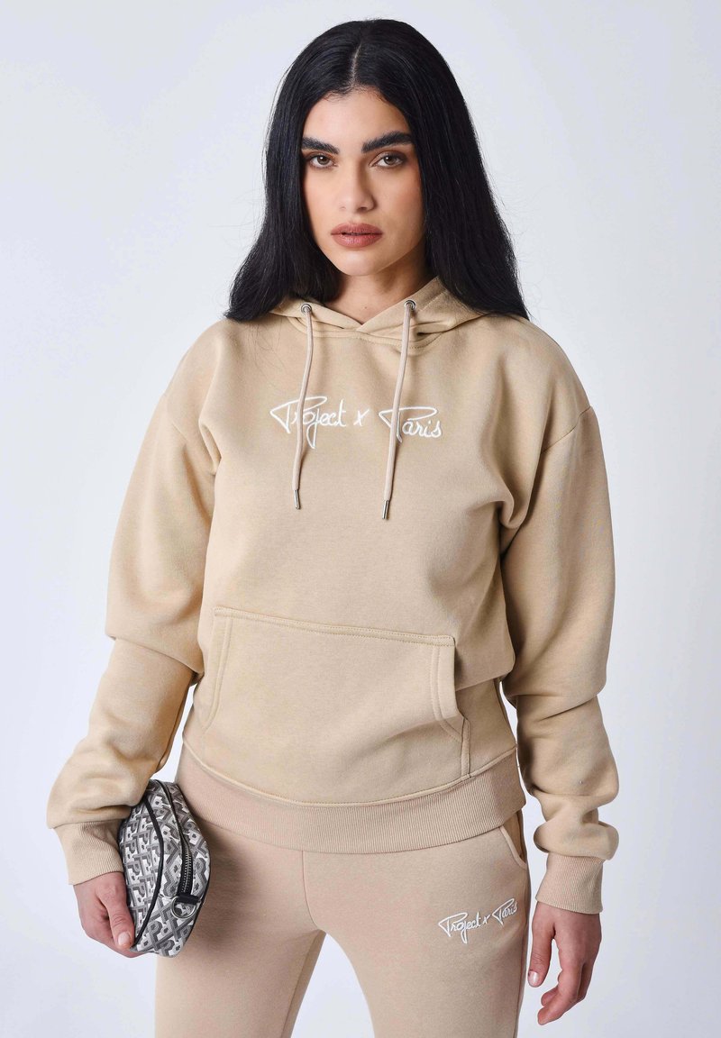 Sudadera con capucha color beige, con bolsillo frontal, puños acanalados y cordón ajustable. Logo bordado "Project x Paris" en blanco. Material de algodón suave.