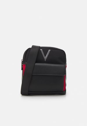 Compatta borsa a tracolla nera con tasca frontale a patta, pannelli laterali rossi, tracolla regolabile e logo argento a forma di V sulla parte superiore frontale.