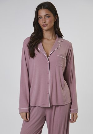 El conjunto de pijama de canalé rosa presenta mangas largas, un frente de botones, un bolsillo en el pecho y ribetes blancos en el collar y los puños.