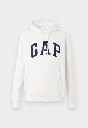 Hvit hettegenser med frontlomme og marineblå "GAP" bokstaver over brystet, med justerbare snorer i hetten.