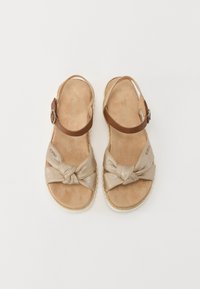 Bruine leren sandalen met een geknoopte gouden stoffen strik. Zacht beige voetbed, jute-achtige textuur van de zool, platte ontwerp, casual stijl.