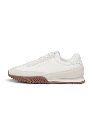 White low-top sneaker with beige suede accents, white laces, and brown textured rubber sole.