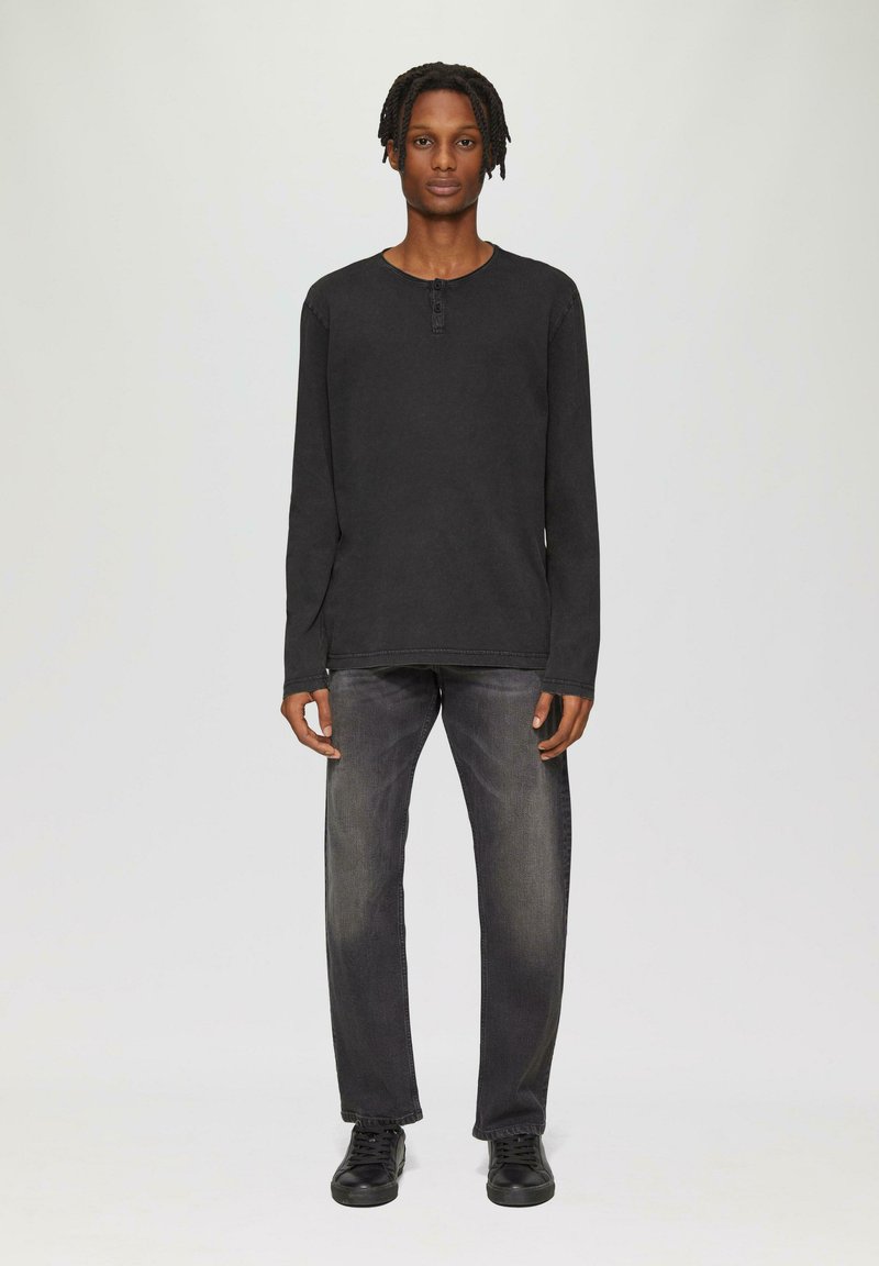 Czarna koszula z długim rękawem i okrągłym dekoltem, z zapięciem na dwa guziki, w połączeniu z ciemnoszarymi dżinsami prostymi oraz czarnymi sneakersami.