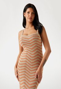 Sukienka dziana z wzorem w jodełkę w kolorach pomarańczowym i beżowym, z wąskimi cienkimi ramiączkami i dopasowanym krojem.