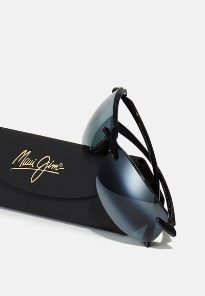 Černé sluneční brýle Maui Jim s polo-rámovým designem, gradientními čočkami a zakřivenými nožičkami, vystavené na černém pouzdře se zlatým logem.