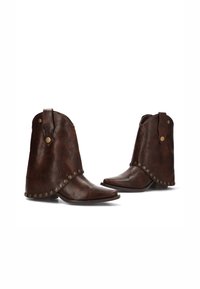 Botas de cuero marrón hasta el tobillo con punteras puntiagudas, remaches decorativos a lo largo del borde y puños doblados. Textura suave con un acabado mate.
