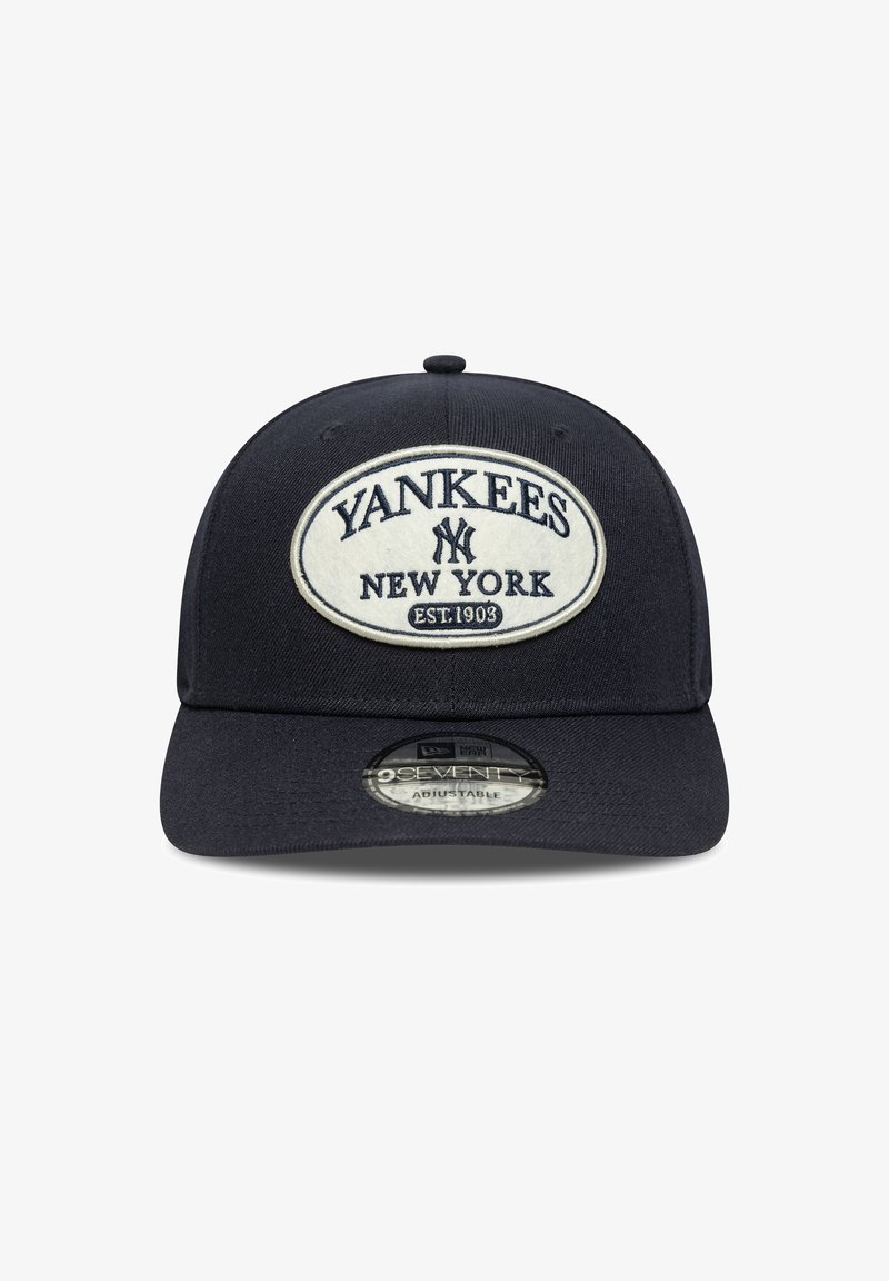 Fekete, testhezálló sapka, ovális fehér folttal. A felirat: "YANKEES NEW YORK EST. 1903." Ívelt napellenzővel és állítható hátsó résszel rendelkezik.