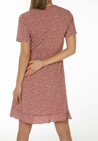 Kortärmad klänning med röd blommig tryck, lätt tyg, rund halsringning, knälång med en volangkant, har små vita blommönster.