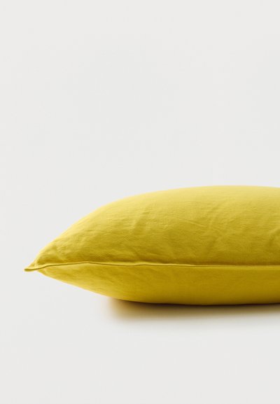Coussin rectangulaire jaune vif avec une housse en tissu lisse, posé à plat sur une surface blanche.