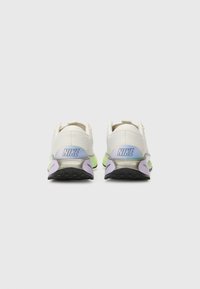Baskets Nike blanches avec dessus texturé, accents pastel verts et violets, talon arrondi et bout renforcé. Logo "NIKE" sur le talon.