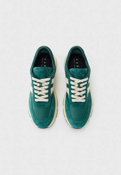 Pair of green and beige lace-up sneakers with suede and leather details, photographed from above on white background.
