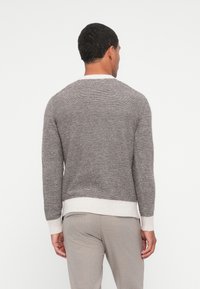 Sweater cinza riscado com mangas longas e decote redondo. Apresenta um acabamento canelado em branco na parte inferior e nos punhos. Textura suave, ajuste casual.