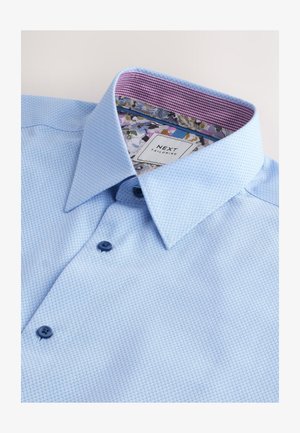 Camicia a quadri azzurri con colletto strutturato, bottoni blu scuro e fodera interna del colletto con motivo floreale.