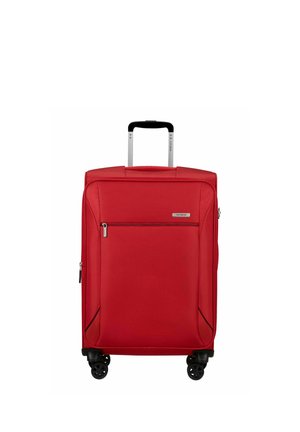 Valise souple rouge avec poche avant zippée, poignée télescopique et quatre roues pivotantes noires sur fond blanc.