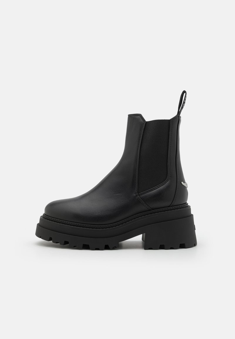 Botas Chelsea negras de cuero liso con paneles laterales elásticos, suela de goma gruesa y estriada, y una lengüeta en la parte trasera.