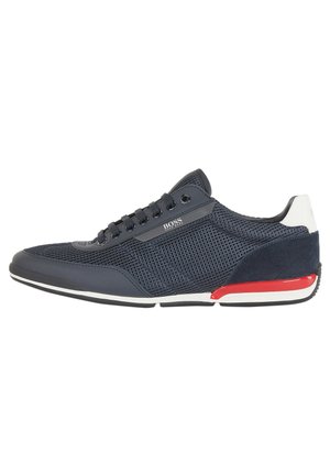 Marineblauwe sneakers van mesh en suède materiaal, met een witte hielaccent en rode details op de zool. Klassiek vetersluitingen ontwerp.