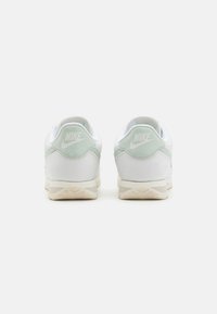 Valged Nike'i tenniset jalatsid, mille kant on hele roheline, tekstuuriga nahaga pealmine osa ja beež kummitald.