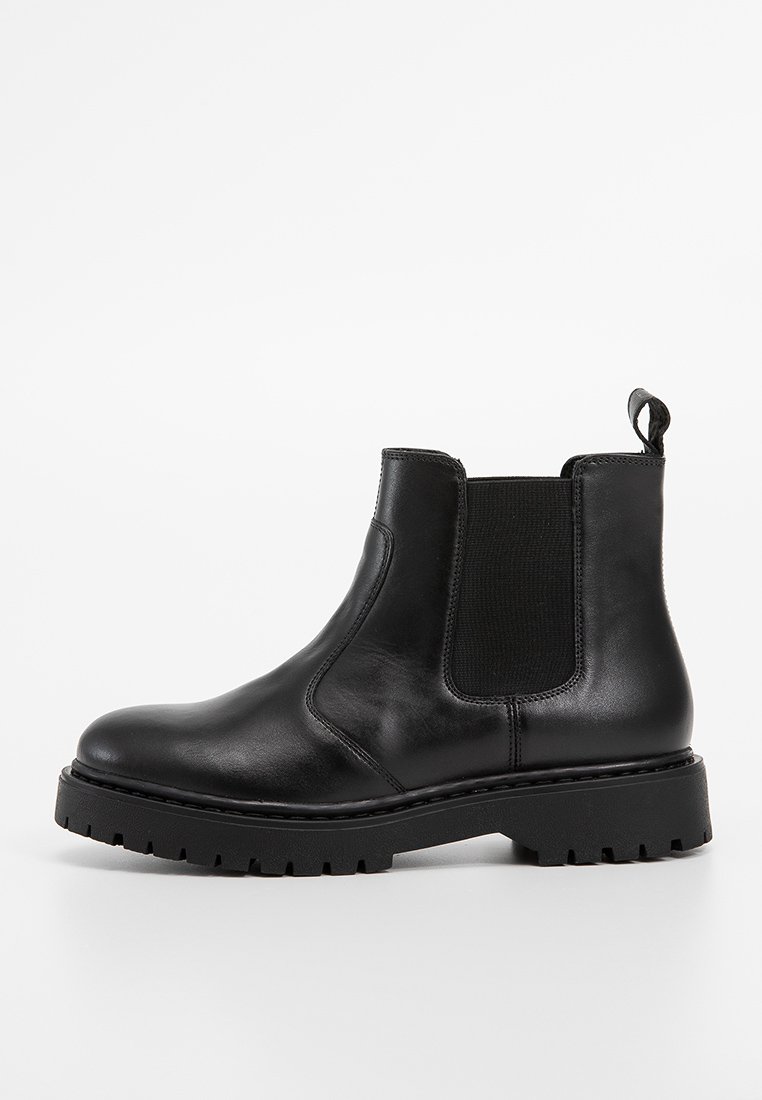 Bottes Chelsea en cuir noir avec des panneaux élastiques sur les côtés, bout arrondi, semelle en caoutchouc épaisse et une languette à l'arrière pour un enfilage facile.