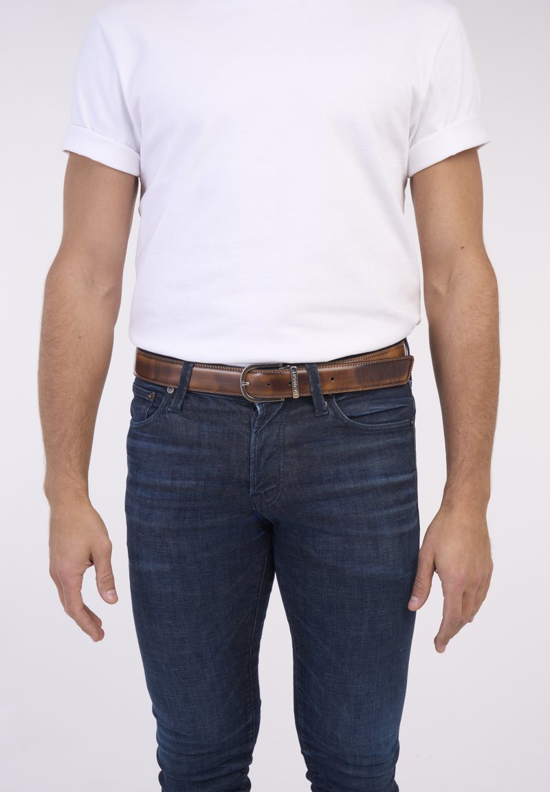 White cotton t-shirt with rolled sleeves worn with dark blue denim jeans. Brown leather belt with a round metallic buckle.