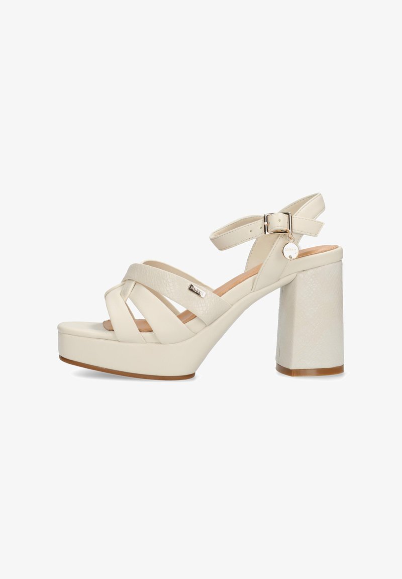 Sandalias de tacón alto en color crema con tiras entrecruzadas, correa ajustable en el tobillo y un tacón de bloque texturizado. Presenta un detalle de marca metálico.