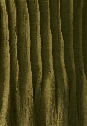 Tekstūrēta zaļa auduma virsma ar vertikālām krokām un neregulārām līnijām, parādot sarautu virsmu un mīkstu, nedaudz spīdīgu apdari.