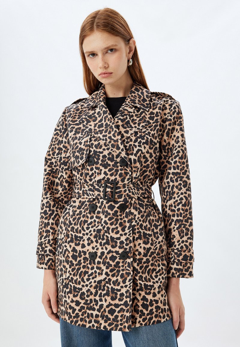Trench coat de estampado de leopardo con cintura ceñida por un cinturón, diseño de doble botonadura y botones negros. Fabricado en tela ligera con una textura suave.