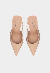 Beżowe baleriny na płaskim obcasie z lakierowanej skóry ekologicznej, z cienkimi paskami i odsłoniętymi piętami, oznaczone jako wegańskie i bez okrucieństwa, przedstawione z góry na białym tle.