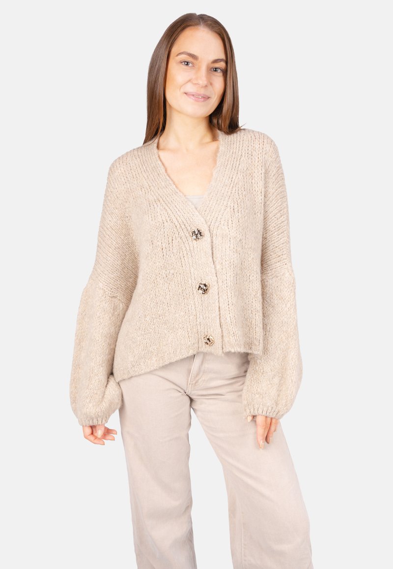 Beige gestrickte Strickjacke mit V-Ausschnitt, drei dekorativen Knöpfen und voluminösen Ärmeln; aus einem weichen, strukturierten Garn hergestellt.