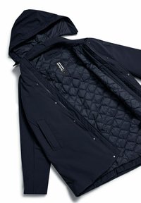 Parka impermeabile blu navy con cappuccio, dotata di fodera trapuntata, bottoni a pressione e tasche laterali. Texture liscia, design pratico.
