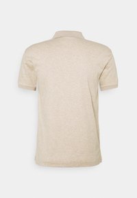 Beige polo-paita, jossa on pehmeä pinta, lyhyet hihat ja klassinen kaulus. Takana on yksinkertainen, hienovarainen heather-kuvio.