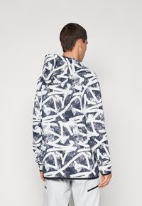 Giacca con cappuccio caratterizzata da un motivo astratto blu navy e bianco, maniche lunghe e vestibilità rilassata. Il materiale sembra liscio con una finitura opaca.