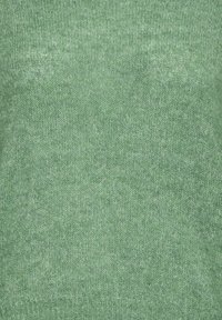 Gros plan d'un tissu tricoté vert doux avec une texture fine et un ourlet côtelé en bas.