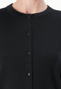 Cardigan nero a maglia con scollo rotondo, dotato di chiusura frontale con bottoni e cinque bottoni neri. Texture liscia con un motivo di tessuto uniforme.