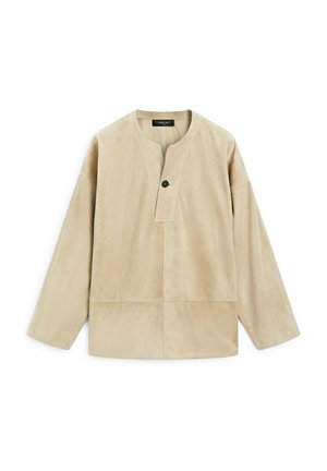 Beżowa zamszowa bluzka z okrągłym dekoltem, długimi rękawami i jednym guzikiem. Gładka tekstura, luźny krój i widoczne szwy.