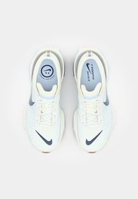 Nike ZoomX running shoes in light blue and white with textured upper, lace closure, dark blue Swoosh, and cushioned sole.