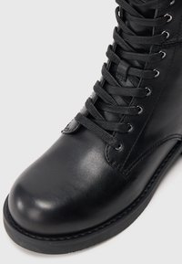 Must mustankad nahast kingad ümarate varvastega, tekstureeritud pind, metallist silmad ja paelad. Tugev kummist tald nähtava õmblemise detailiga.