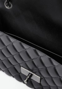 Schwarze gesteppt Handtasche aus glattem synthetischem Material, mit einem Metallverschluss und einer Kettenhenkel, mit strukturierter Oberfläche und schlankem Design.