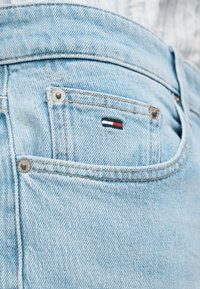 Τζιν παντελόνι σε ανοιχτό μπλε χρώμα με μπροστινή τσέπη που έχει μικρό λογότυπο σε κόκκινο, λευκό και μπλε. Υφή υφάσματος με εμφανείς ραφές.