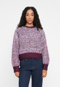 Suéter de malha em roxo, rosa e branco com uma textura grossa. Apresenta um decote redondo e punhos e barra canelados, com um design cropped.