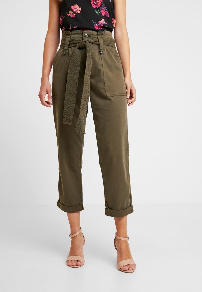 Olivgröna högmidjade byxor med bälte, med uppvullade fållar och två framfickor, tillverkade av ett lätt bomullsmaterial.