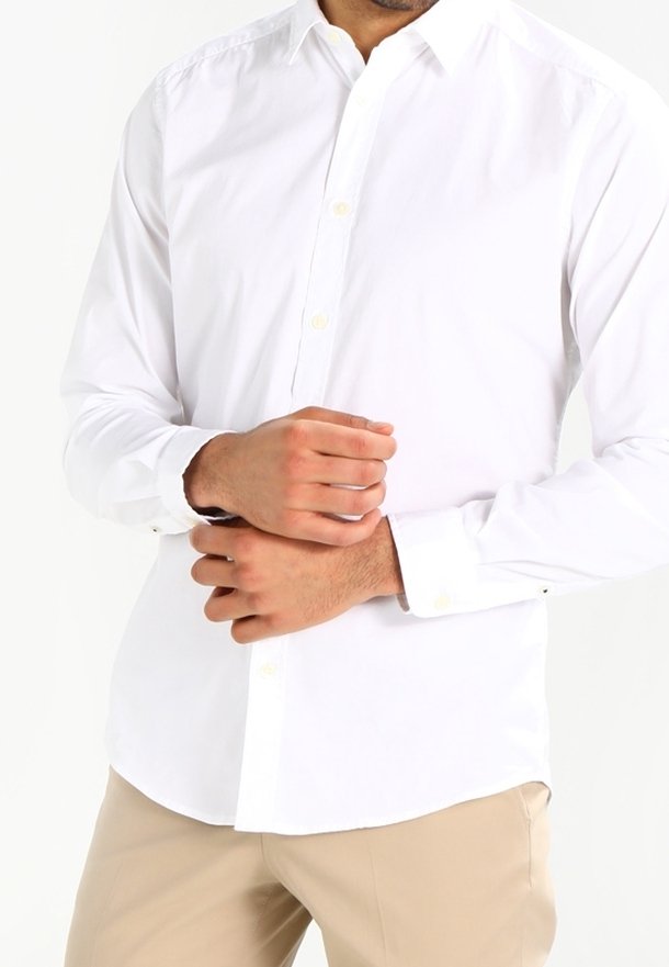 Biała koszula zapinana na guziki z długim rękawem, wykonana z bawełny, z kołnierzykiem i mankietami. Posiada prosty krój u dołu oraz subtelną fakturę materiału.
