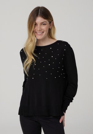 Maglione nero a maglia con maniche lunghe, decorato con accenti di perle bianche sparse sul petto. Orlo leggermente svasato.