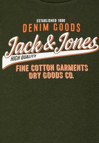 Camiseta de algodón verde oliva con texto en blanco y naranja: "Jack & Jones", "Denim Goods" y "Fine Cotton Garments Dry Goods Co."