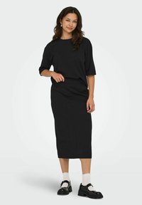 Zwart twee-delig outfit met een losvallende top met korte mouwen en een bijpassende midi-rok. Draagt het met chunky zwarte schoenen en witte sokken.