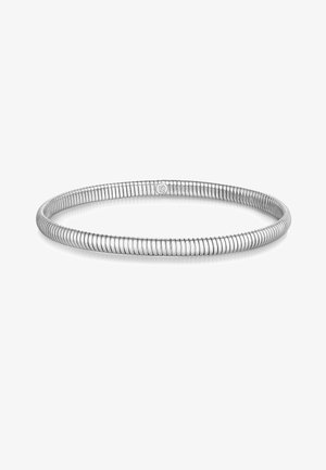 Rugalmas ezüst színű tekercselt karkötő kis kör alakú kapoccsal, amelyen levél motívum látható, fehér háttéren.