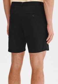 Czarne szorty wykonane z gładkiego materiału, z dwiema tylnymi kieszeniami z guzikami oraz płaskim pasem. Prosty design, długość do połowy uda.